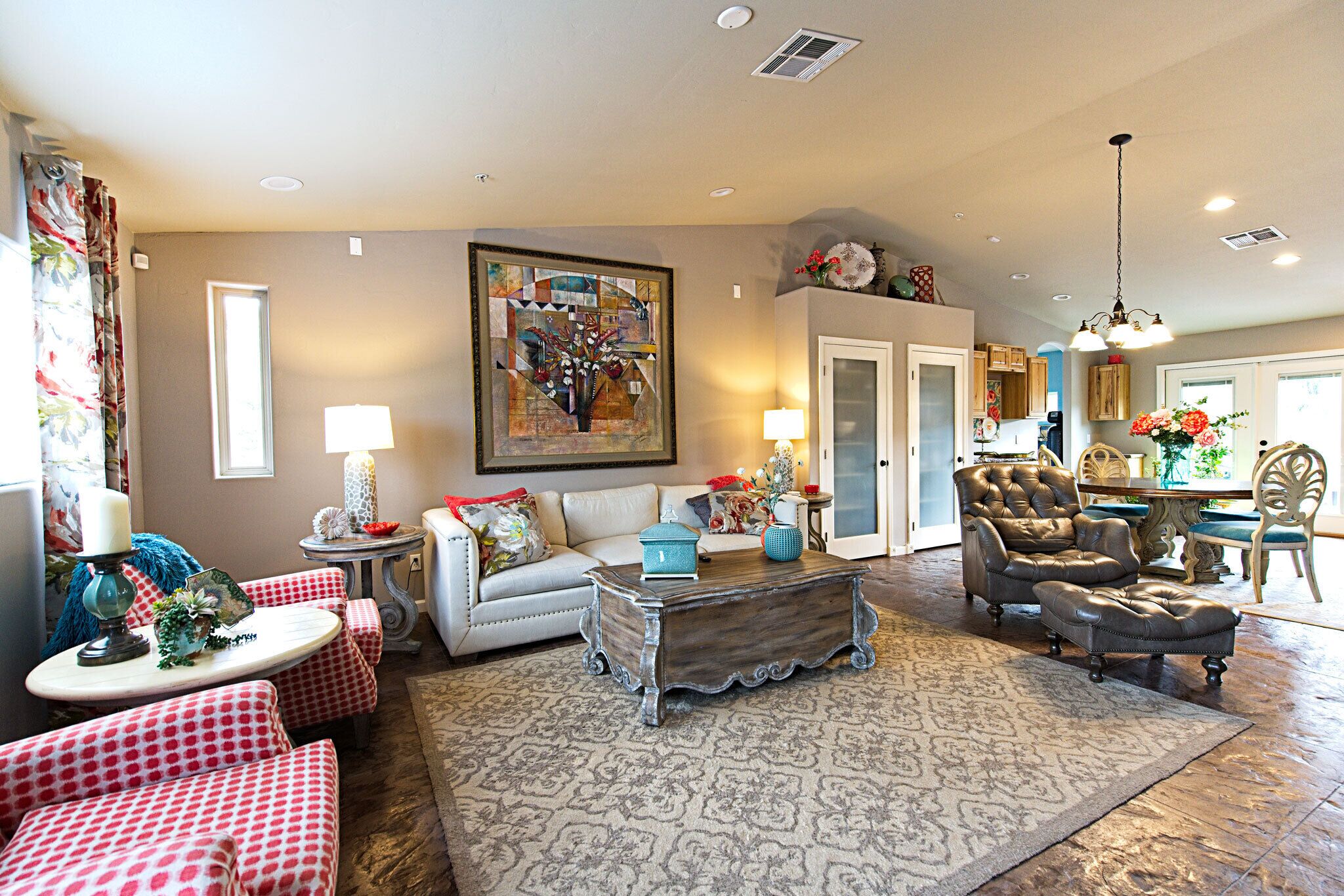 A living room with a sofa, armchairs, a coffee table, and a rug. There is a dining area with a table and chairs.