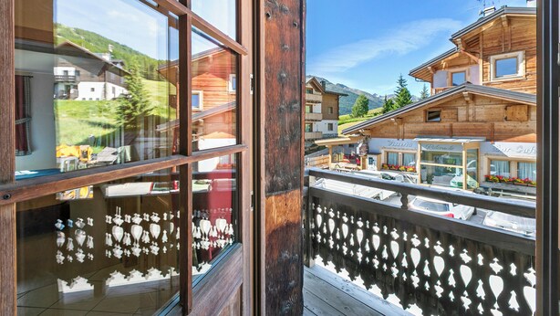 Un balcon en bois offrant une vue sur une montagne et une ville.