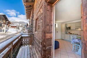 A wooden balcony with snow on the railings, a kitchen with modern appliances, and a view of a snowy mountain landscape. - Archillea, Livigno, Italy (Livigno)