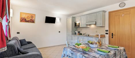 A compact living space with a dining area, kitchen, and a grey sofa.