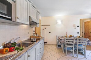 A kitchen with a sink, stove, and dining table set for two. - Archillea, Livigno, Italy (Livigno)