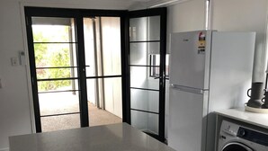 A modern kitchen with a stainless steel refrigerator, a washing machine, and a countertop. - Archer View - 72 Archer Steet, Emu Park (Emu Park)