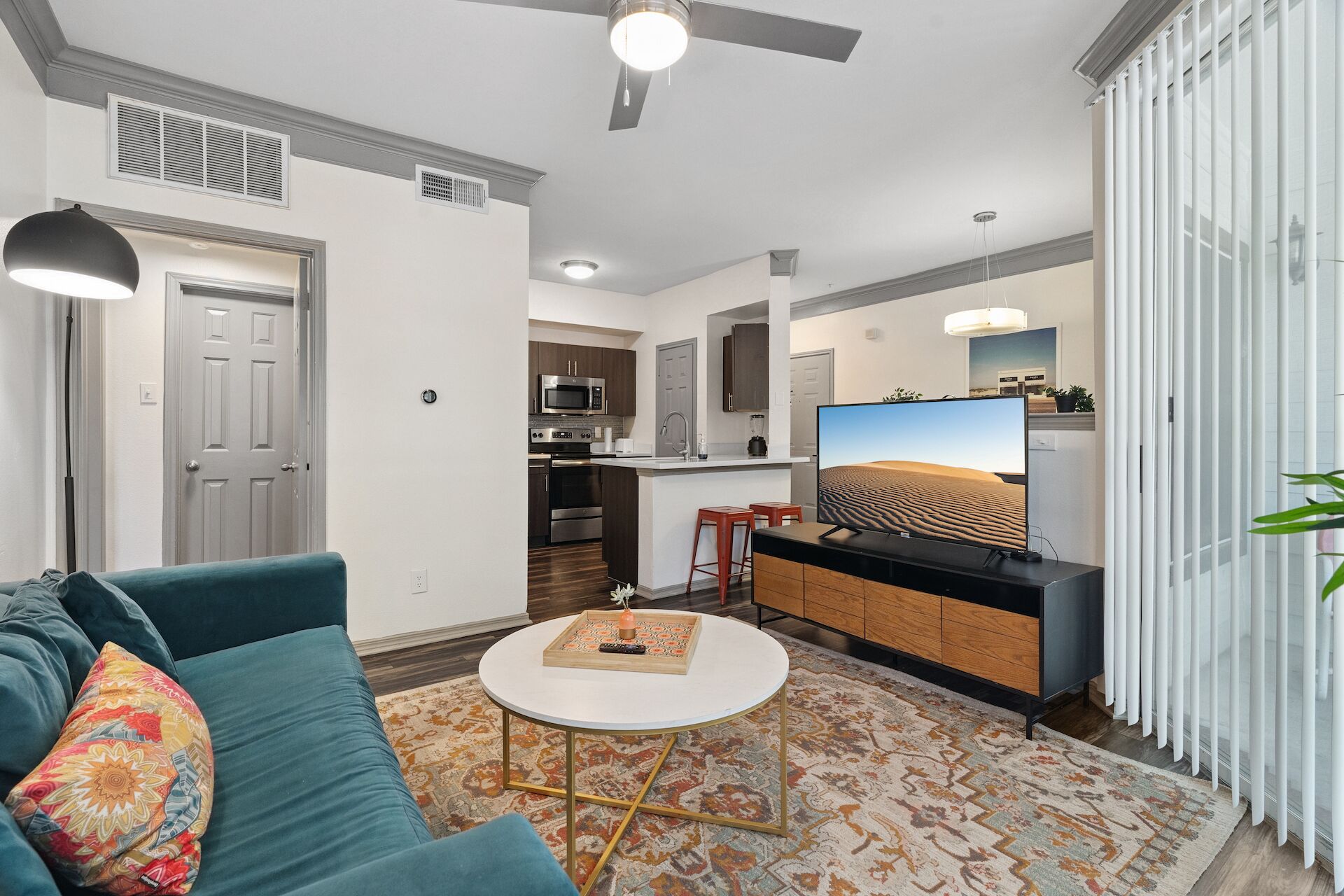 Una sala de estar moderna con un sofá, una mesa de centro, un televisor y una cocina al fondo.