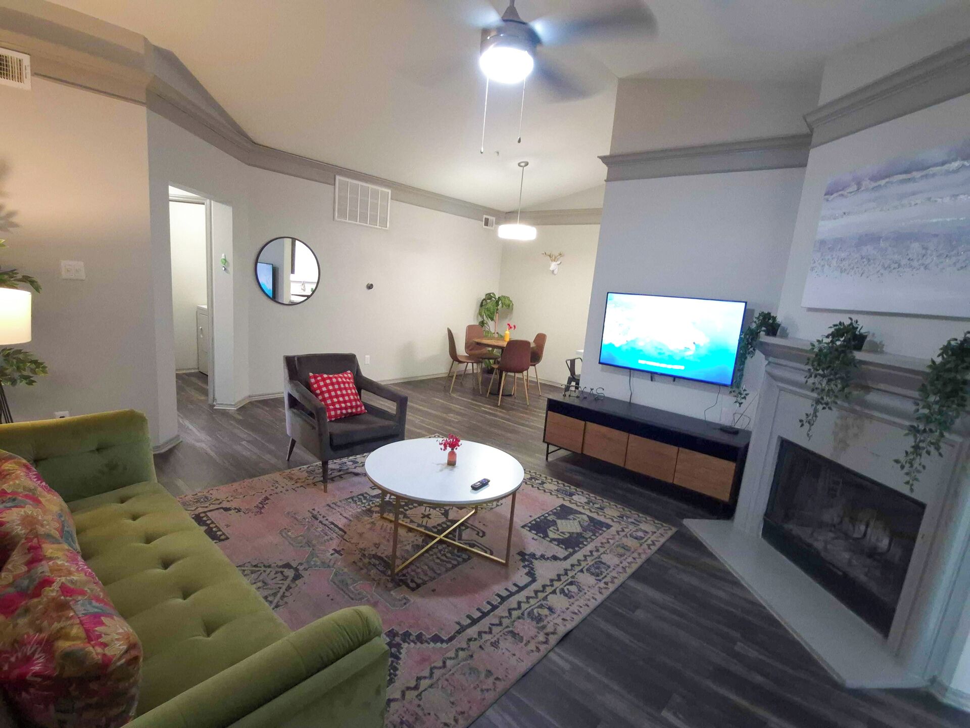 A living room with a green sofa, a round coffee table, a fireplace, and a television.