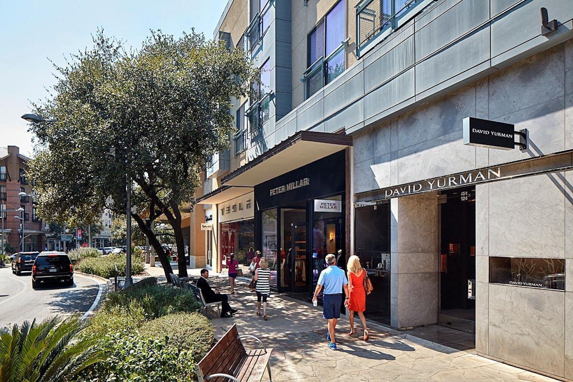 Une vue de rue avec des devantures de magasins, notamment celles de « Peter Millar » et de « David Yurman ».
