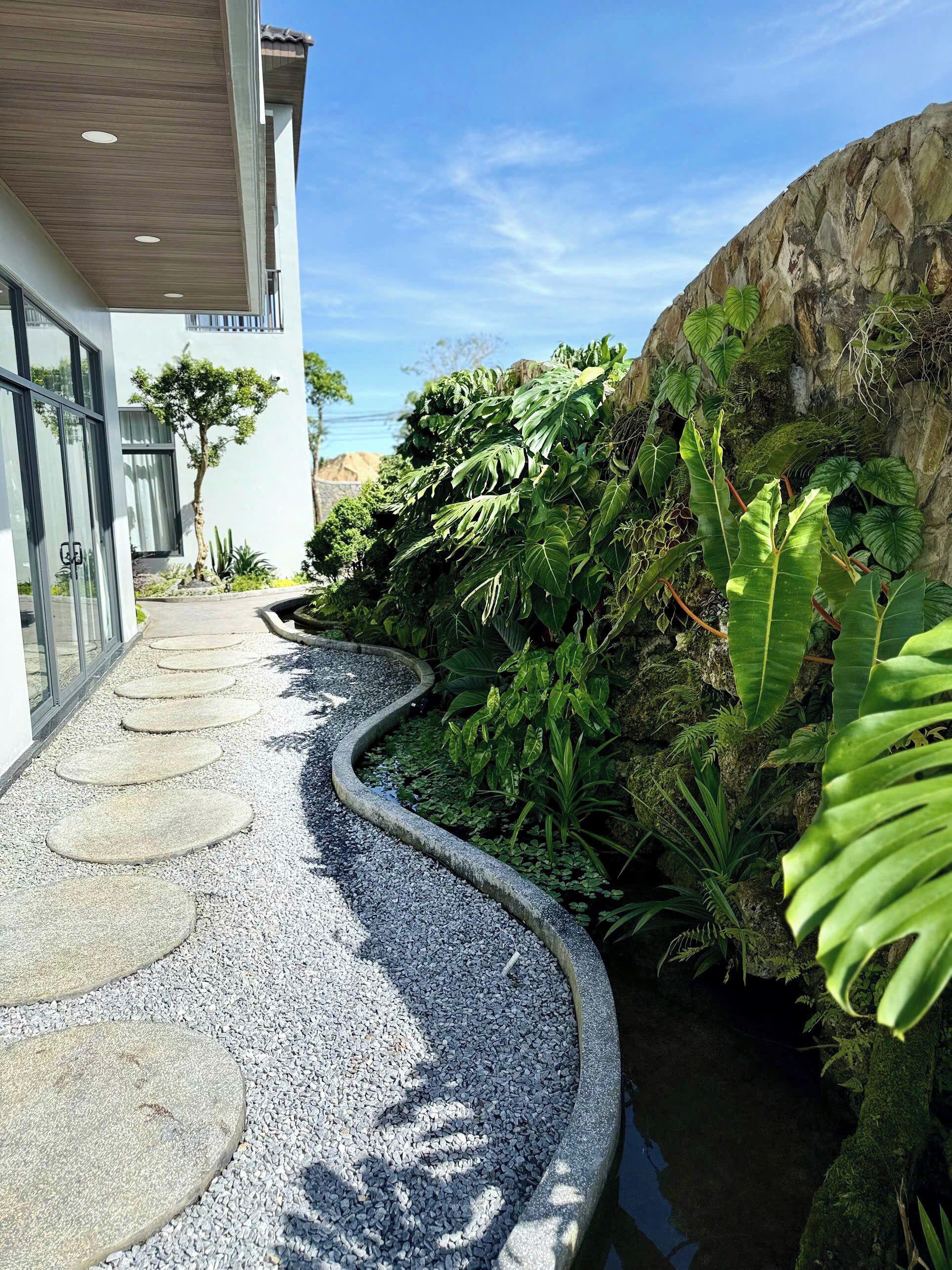 Un sendero con piedras redondas guía hacia un edificio con puertas de vidrio.