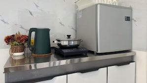 Egy konyha, amelyben rozsdamentes acél munkalap, egy vízforraló, egy hordozható tűzhelyen lévő edény és egy hűtőszekrény található.