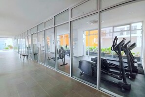 Ein Fitnessstudio mit Trainingsgeräten, Glaswänden und Blick ins Freie.