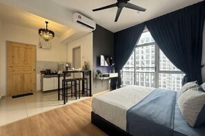 Ein kleines Hotelzimmer mit Bett, Schreibtisch und einer Küchenzeile.