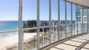 Ein Balkon mit großen Fenstern mit Blick auf Strand und Stadtlandschaft.