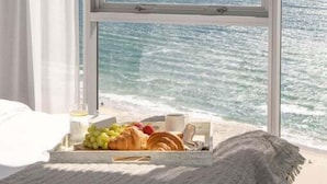 Ein Zimmer mit großem Fenster mit Blick auf ein Gewässer und eine entfernte Stadtlandschaft.