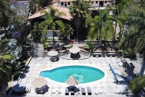 A pool area with a circular pool, lounge chairs, umbrellas, and palm trees. - ANANA Rancho San Rafael Pool and Lake Views (Ajijic)