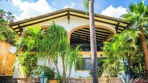 A two-story building with a tiled roof, a balcony, and a stone wall. - ANANA Rancho San Rafael Pool and Lake Views (Ajijic)