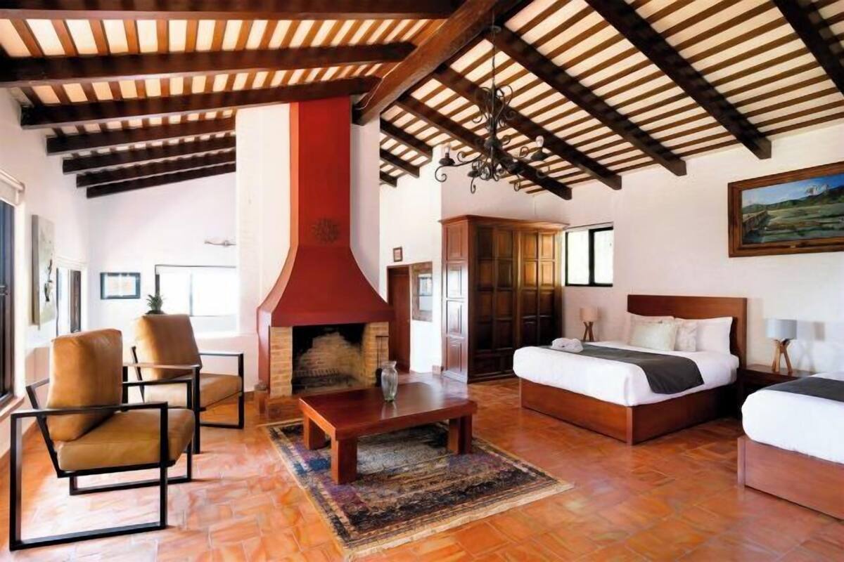 A room with a fireplace, a bed, a sofa, and a dining table.
