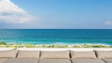 A beach view with a lounge area and ocean in the background.