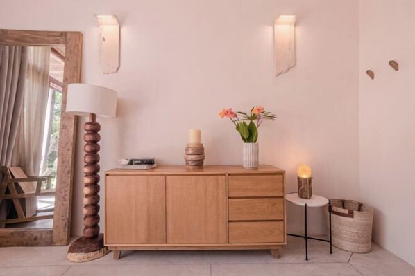 A wooden cabinet with a white vase of flowers, a lamp, and a small table with a candle. - ANANA Casa Kaab Kaan Rooftop pool & Beachfront (Tulum)