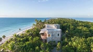 A beachfront property with a small building surrounded by dense tropical vegetation and a clear view of the ocean.