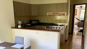 A compact kitchen with a central island, a dining area with a table and chairs, and a visible hallway leading to another room. - Comfortable and safe apartment with river view (Medellín)