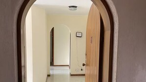 A hallway with a tiled floor, a wooden door, and a number '402' above an archway. - Comfortable and safe apartment with river view (Medellín)