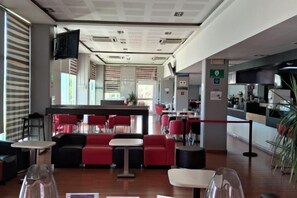A restaurant with red and black seating, a bar area, and a television mounted on the wall.