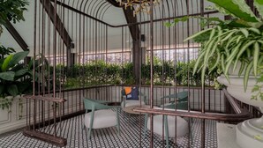 A cozy indoor garden with a metal cage structure, seating area, and potted plants. - Paxtonz KL Walk to Mall & Pool (Petaling Jaya)