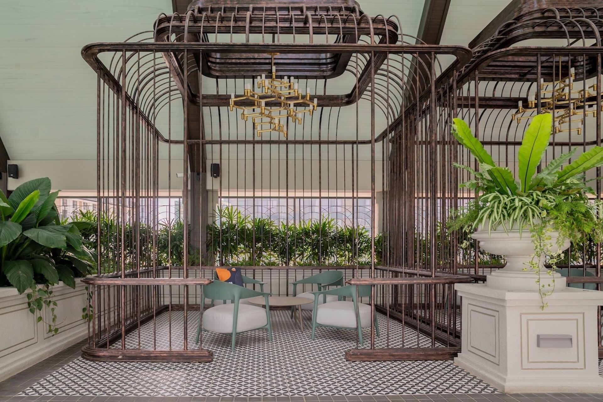 A cozy indoor seating area with a metal cage structure, cushioned chairs, and a patterned floor.