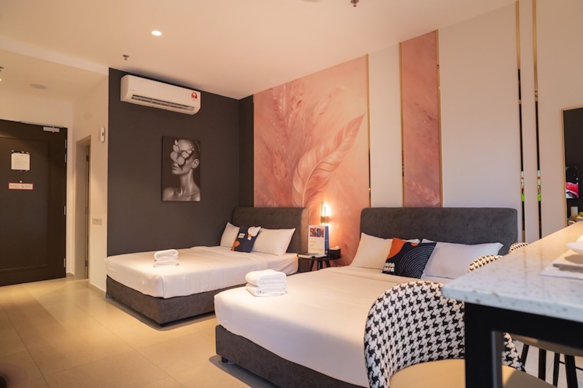 A hotel room with two beds, a desk, and a large wall mural.