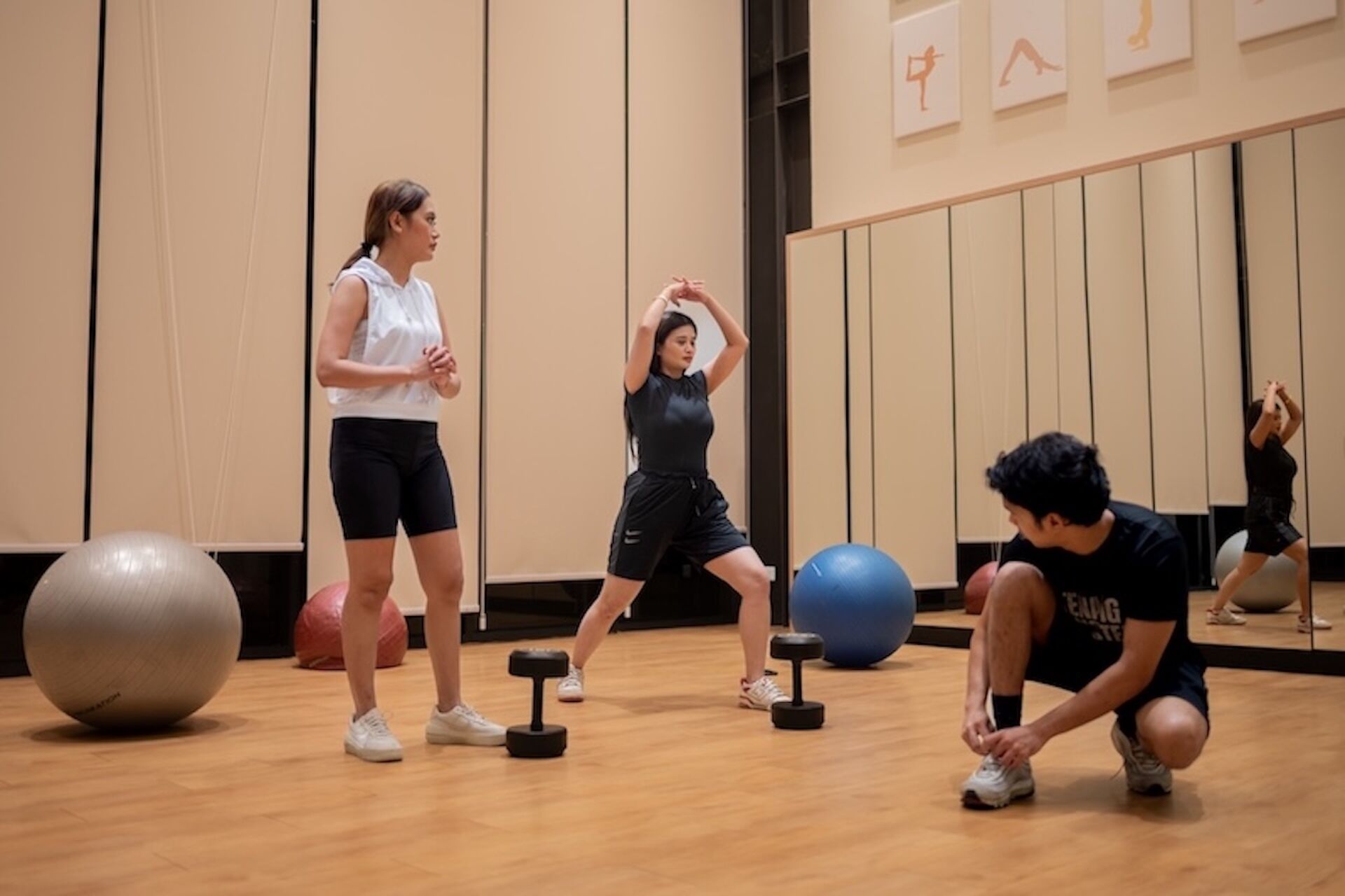 Un gimnasio con equipo de ejercicio, piso de madera y pared de espejos.