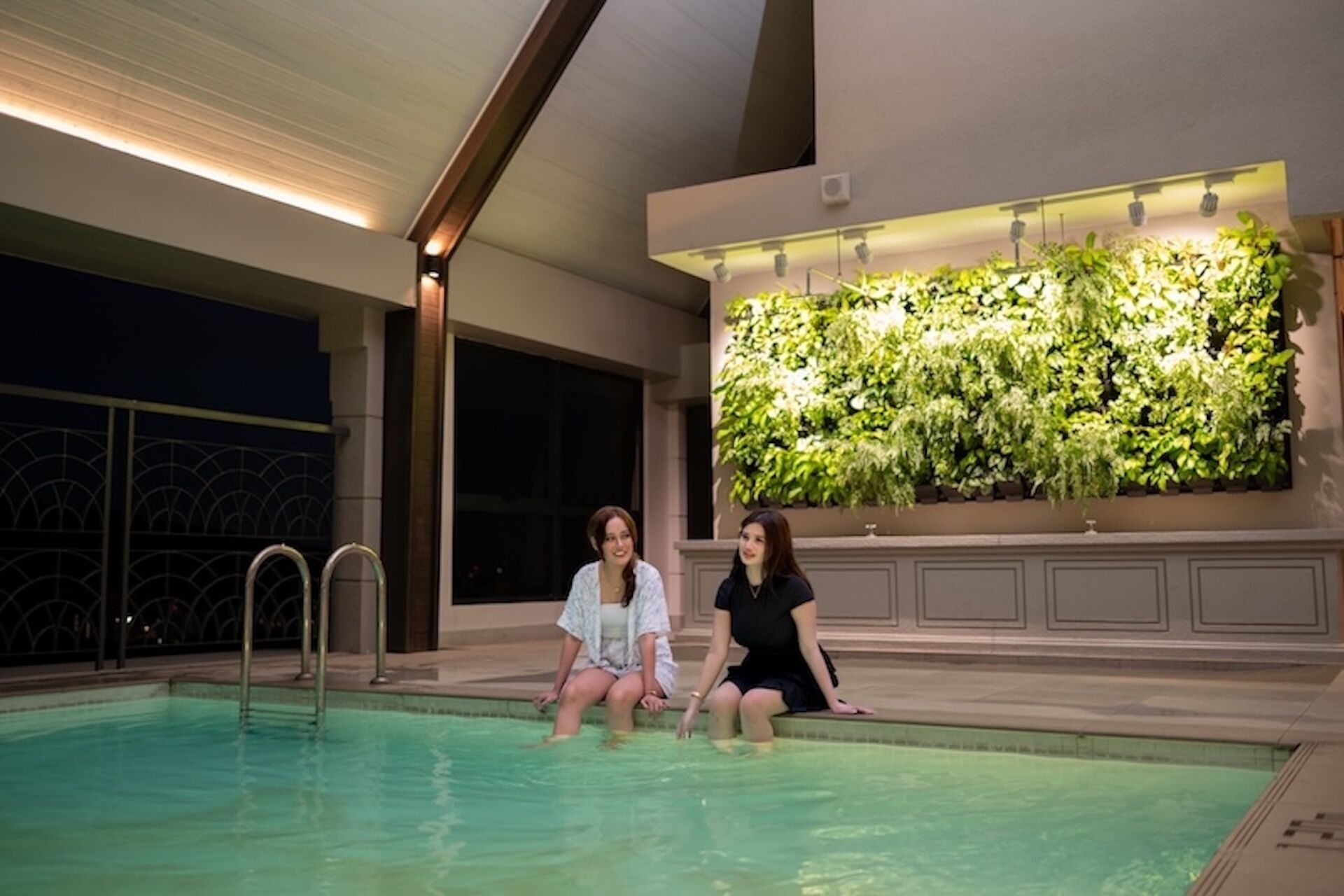 Una piscina al coperto con due persone sedute sul bordo.