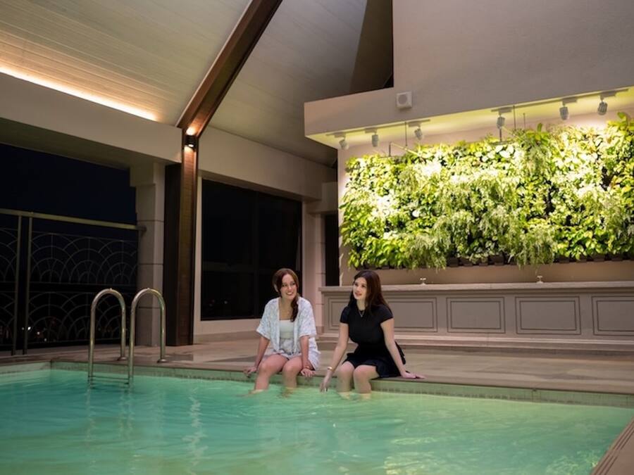 Una piscina al coperto con due persone sedute sul bordo.