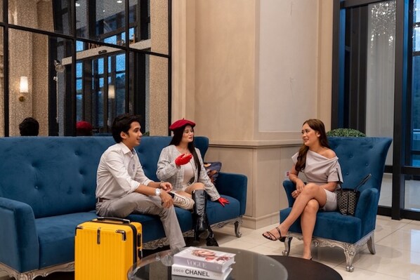 A modern lobby with a blue sofa, a yellow suitcase, and a Chanel book on a table.