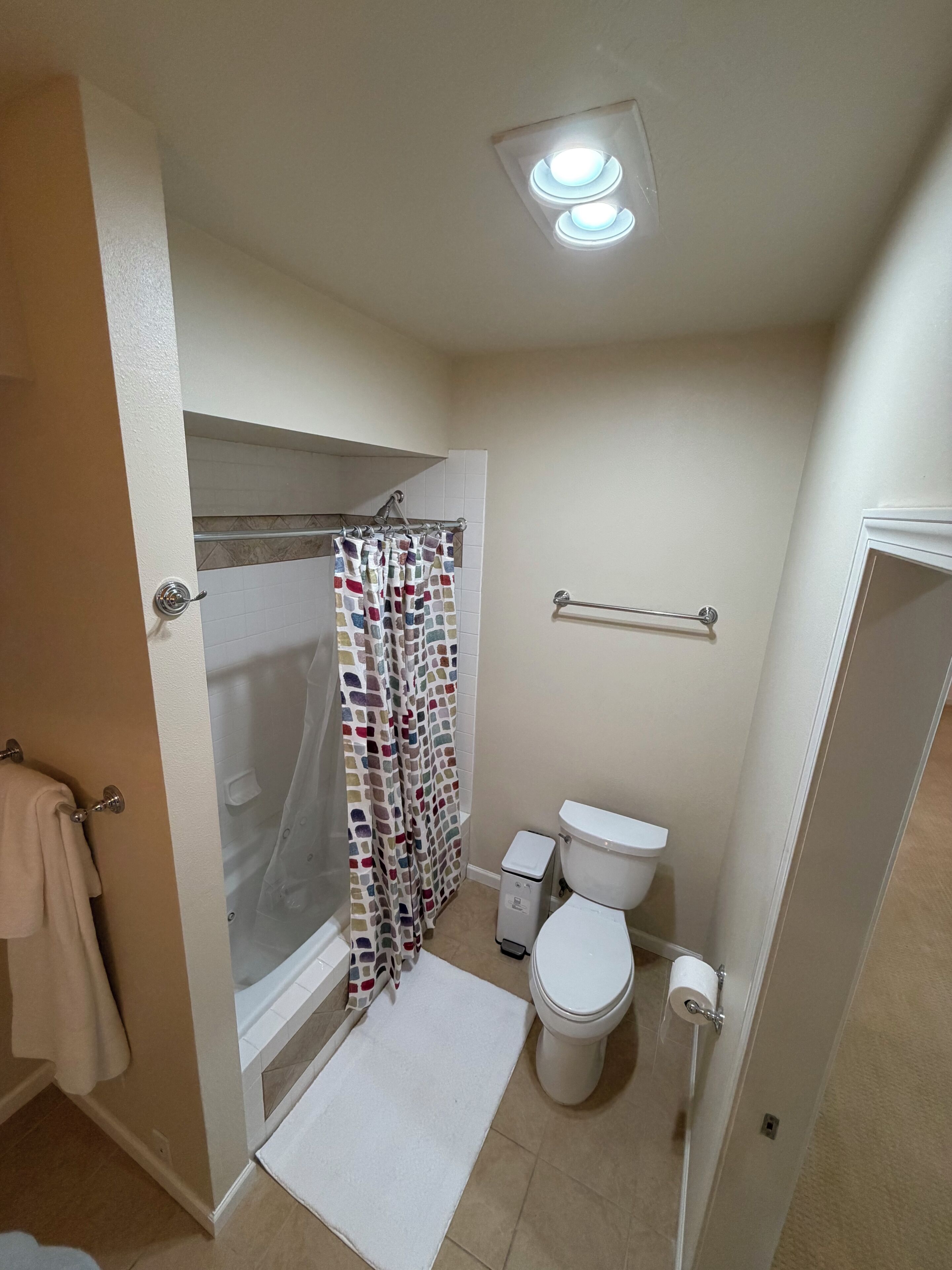 A bathroom with a shower, toilet, and a towel rack.