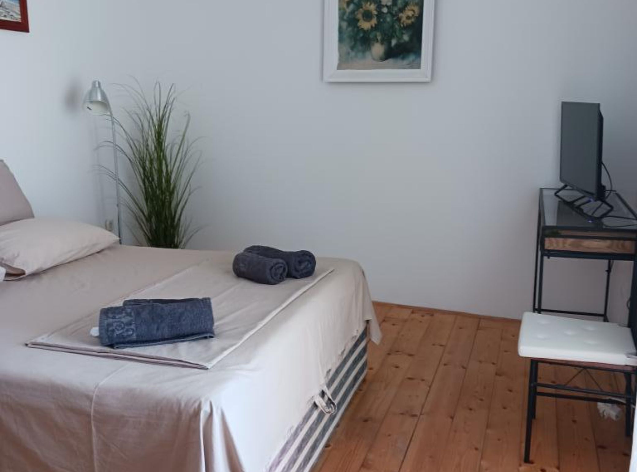 A bedroom with a bed, a desk, a chair, a lamp, and a painting on the wall.