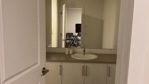 A bathroom with a white sink, a mirror above it, and a door with a handle.