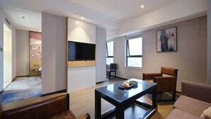 Ein modernes Wohnzimmer mit Fernseher, Couchtisch und Sitzgelegenheiten.