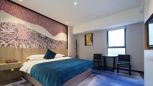 Ein modernes Hotelzimmer mit einem großen Bett, einem Schreibtisch und einem Stuhl.