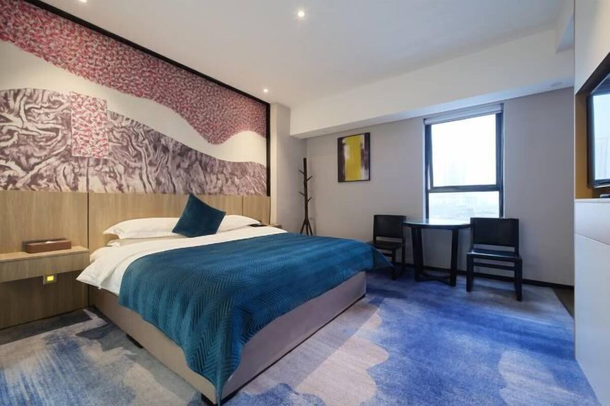 Une chambre d’hôtel moderne, dotée d’un grand lit, d’un bureau et d’une chaise.