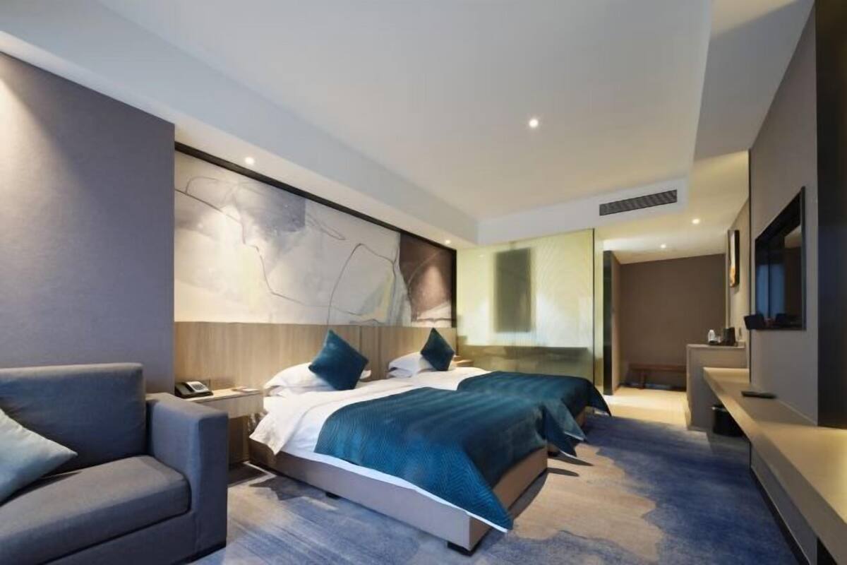 Une chambre d’hôtel moderne avec un grand lit, un canapé, un bureau et une télévision.