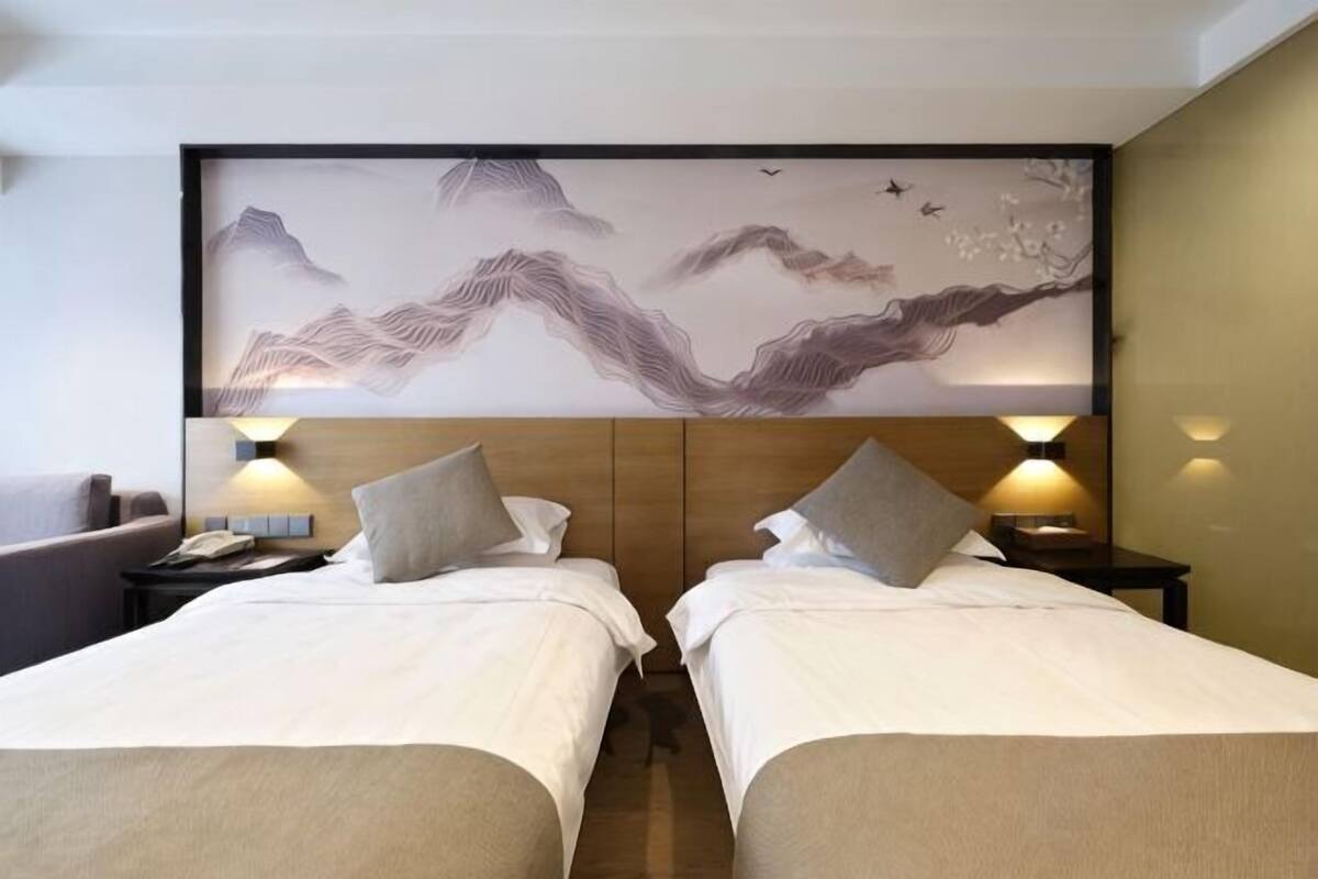Une chambre d’hôtel avec deux lits, une grande fresque murale et des lampes de chevet.
