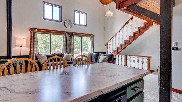 A spacious dining area with a marble table, wooden chairs, and a staircase with a wooden railing.