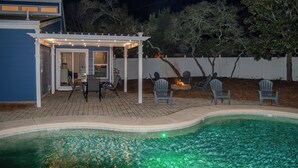 A pool area with a covered patio, chairs, and a small fire feature. - Marvelous 4-bedroom house with AC in Miramar Beach (Miramar Beach)