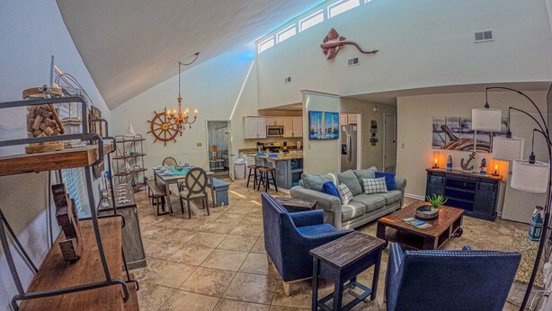 A spacious living area with a high ceiling, a dining table, sofas, and a kitchen in the background. - Marvelous 4-bedroom house with AC in Miramar Beach (Miramar Beach)