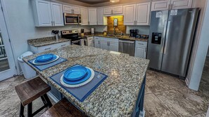 A modern kitchen with granite countertops, stainless steel appliances, and white cabinetry. - Marvelous 4-bedroom house with AC in Miramar Beach (Miramar Beach)