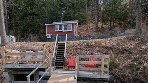 Un muelle de madera que conduce a una pequeña construcción con fachada roja.