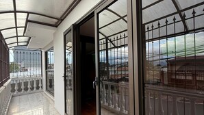 Un balcon fermé offrant une vue sur la mer, un sol carrelé et une porte vitrée donnant sur un espace intérieur.
