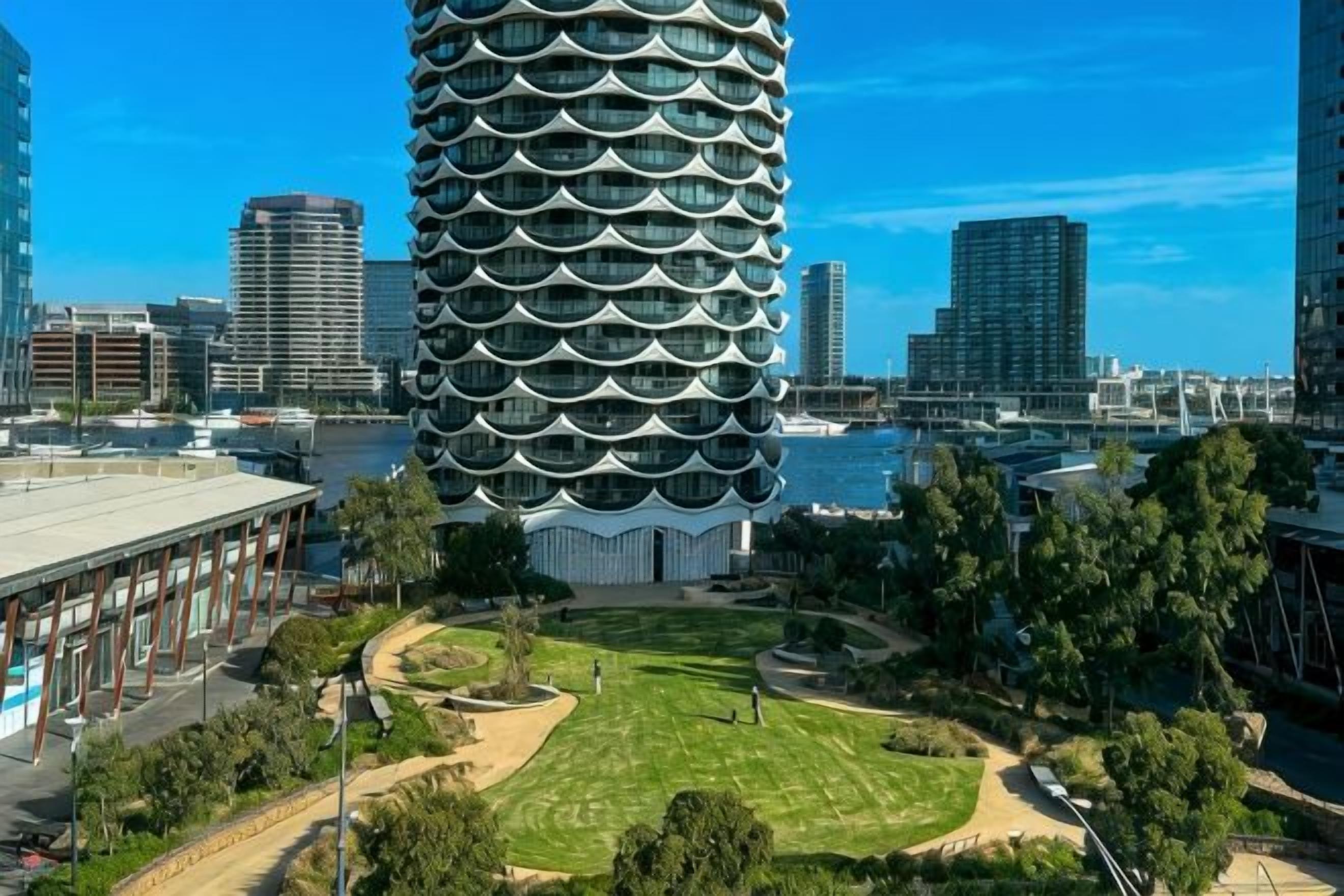 A modern building with a unique circular design, surrounded by a well-maintained park and other urban structures.