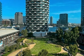 Un edificio moderno con un diseño circular distintivo, rodeado de un parque cuidado y otras construcciones urbanas.