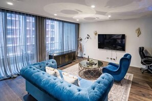 Un salon moderne avec un canapé bleu, une table basse et un téléviseur fixé au mur.