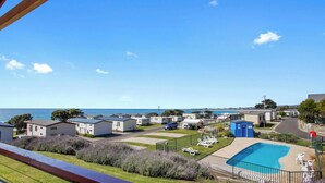 A coastal caravan park with multiple mobile homes, a swimming pool, and a view of the sea. - Ultra-Modern Coastal Living (Apollo Bay)
