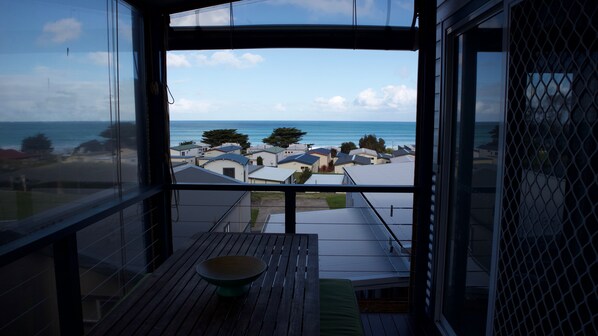 A balcony with a view of the sea and nearby houses.